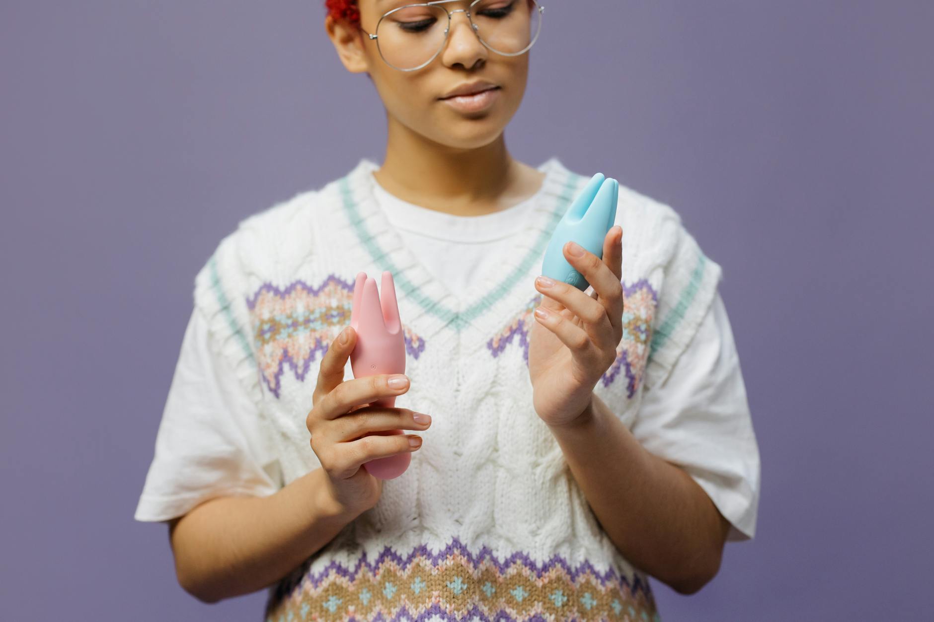 Hand holding blue silicone clitoral vibrator showing texture and design detail