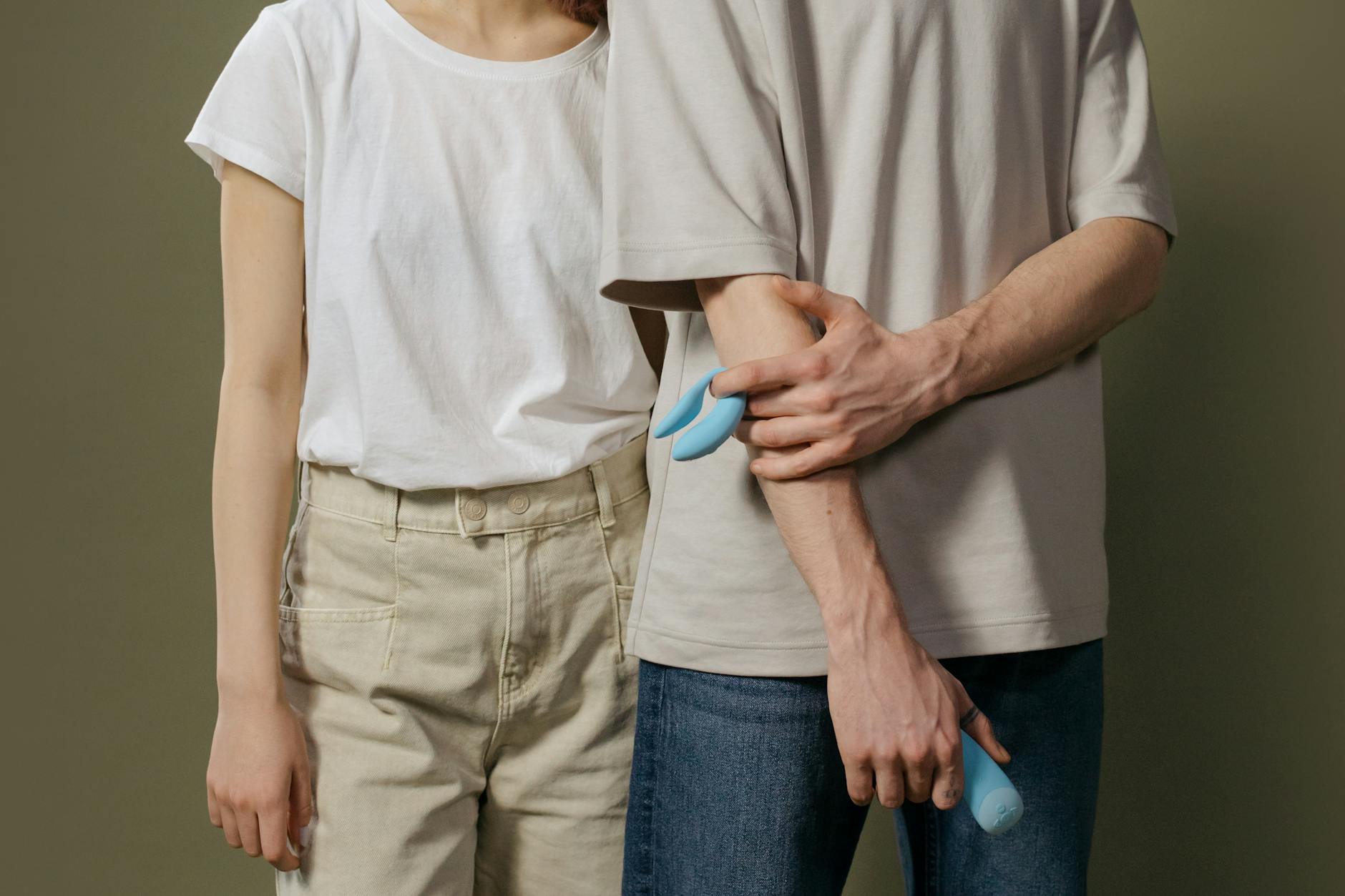 Woman holding blue and pink clitoral vibrators in a moment of self-awareness