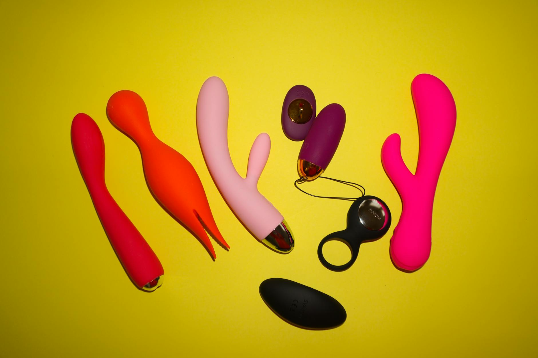 Woman holding blue and pink silicone vibrators in contemplative pose